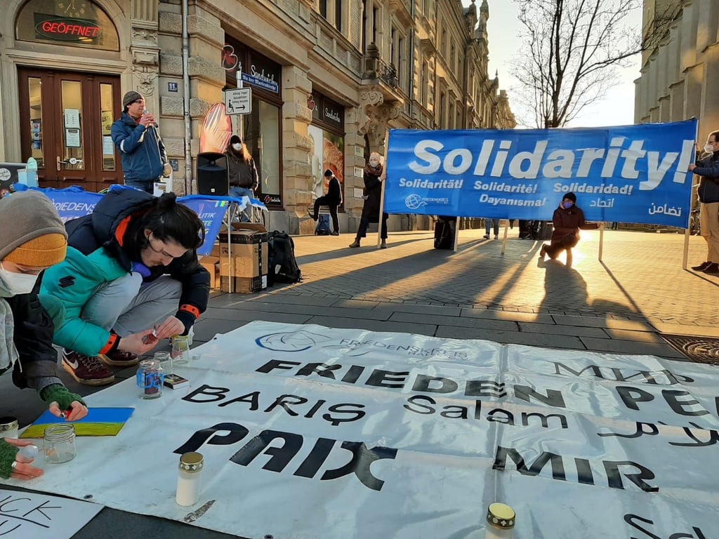 Neben der Marktkirche hat der Friedenskreis Halle ein Transparent ausgebreitet, auf dem nur ein Wort in zahlreichen Sprachen steht: Frieden.