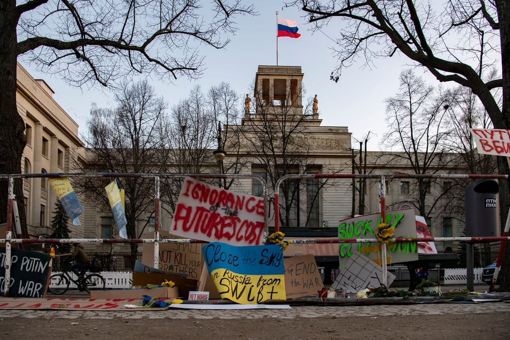 An den Absperrgittern vor der russischen Botschaft in Berlin haben Menschen Plakate angebracht.