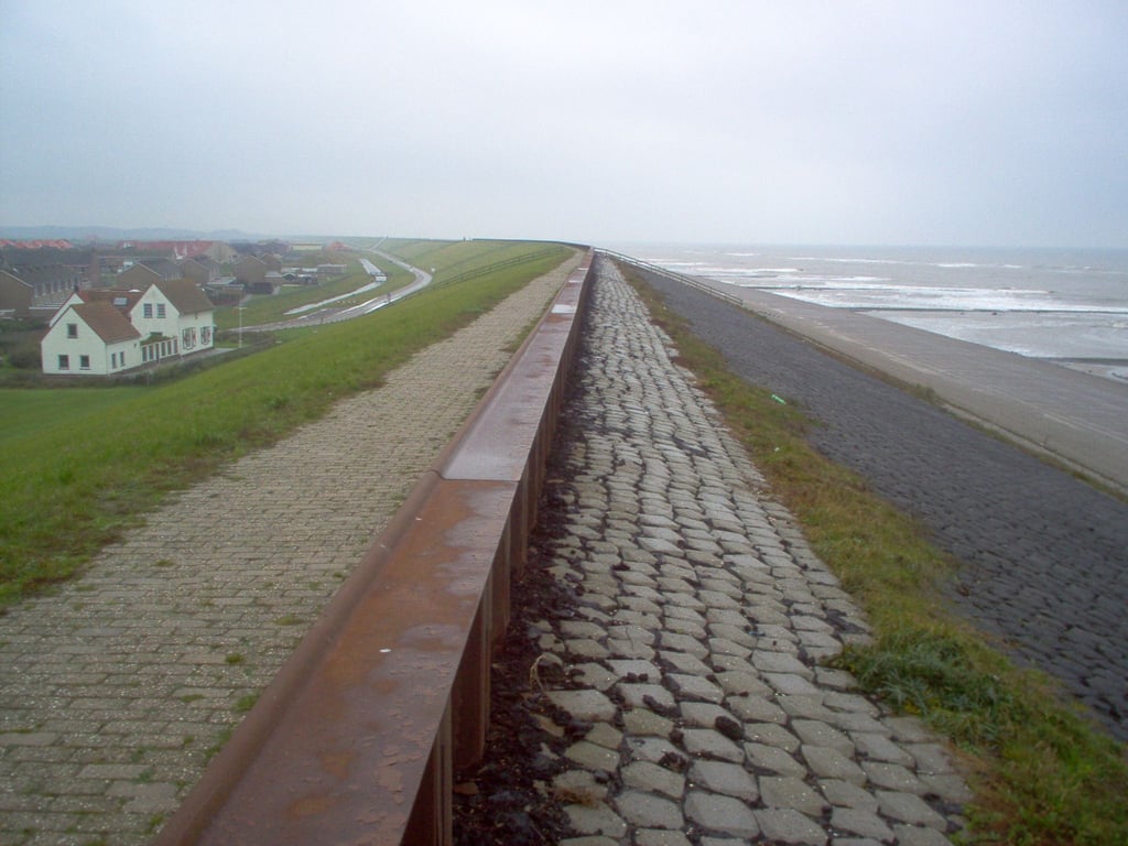 Ein Ort liegt an einem Deich hinter einem Strand in den Niederlanden.