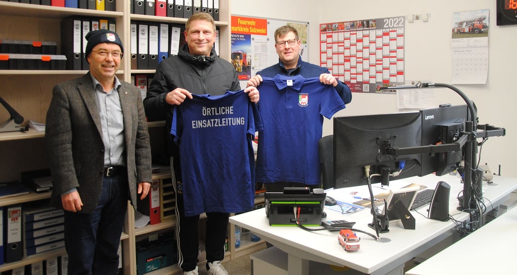 VG-Bürgermeister Michael Olms (von links) bedankte sich im neu eingerichteten Lagezentrum stellvertretend bei Mathias Gose und Marco Zander von der örtlichen Einsatzleitung für das Engagement bei den Sturmeinsätzen und überreichte ihnen die neu angeschafften Trikots und Mützen.