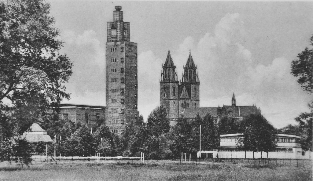 Eine historische Ansichtskarte zeigt das Gelände der Theaterausstellung mit dem heutigen Albinmüller-Turm und der Stadthalle dahinter. Im Vordergrund sind nicht mehr vorhandene Gebäude zu sehen, im Hintergrund der vergrößert dargestellte Magdeburger Dom.