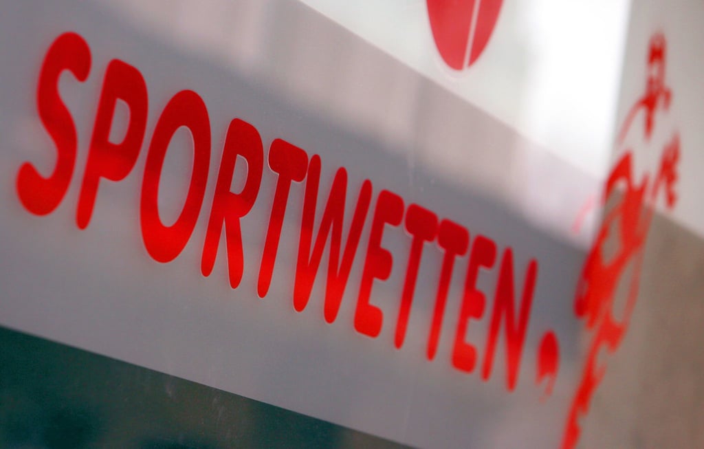 Werbung für Sportwetten klebt an der Schaufensterscheibe eines Wettbüros.