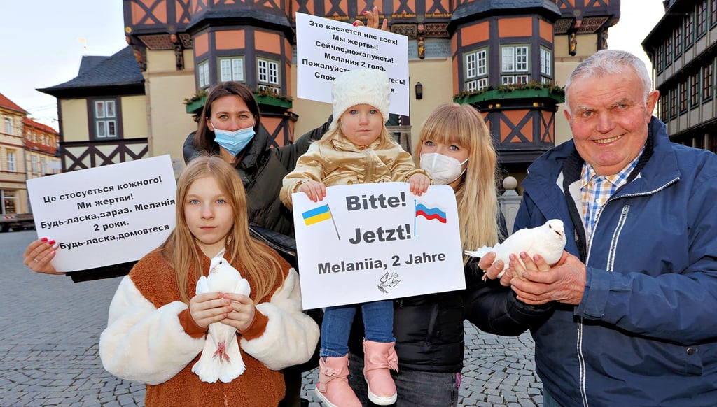 Friedensaktion auf dem Wernigeröder Markt: Die geflüchteten Ukrainerinnen Anna Efimenko (hinten links) und Olga Sydorenko (2. v. rechts) – mit ihren Kindern Melaniia und Arina (links) – bitten mit Taubenzüchter Bernd Rettmer aus Reddeber mit weißen Friedenstauben um ein Ende des Krieges in ihrer Heimat.
