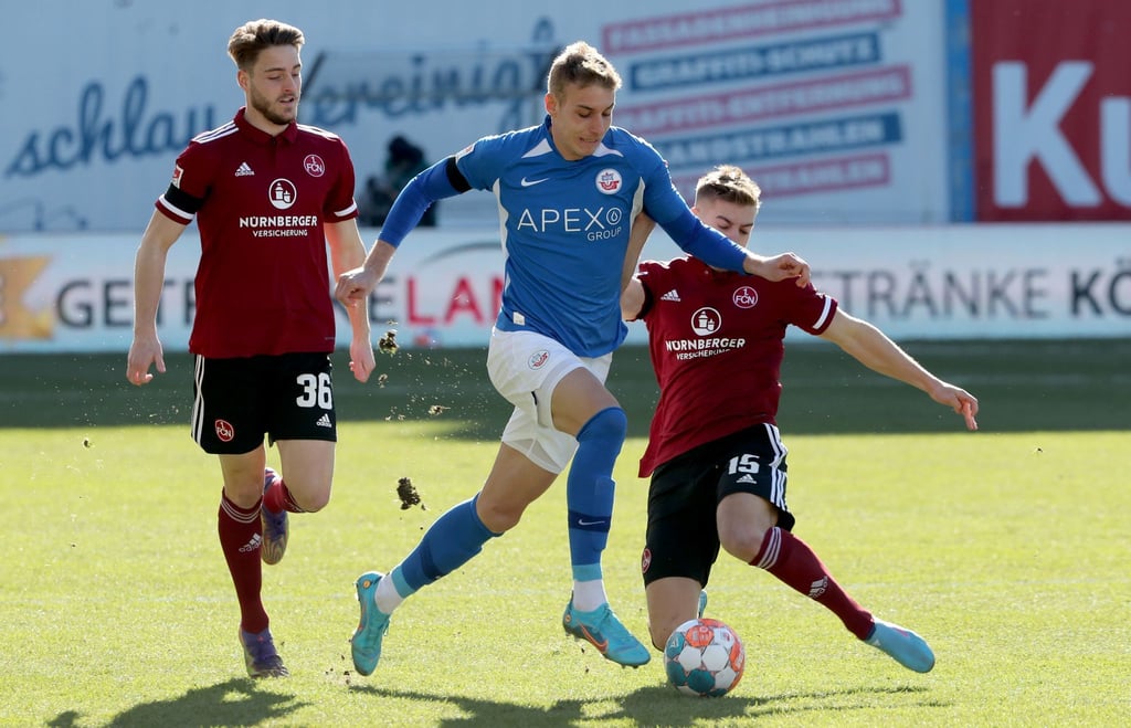 Nürnbergs Lukas Schleimer (l) und Fabian Nürnberger versuchen Hansas Danylo Sikan vom Ball zu trennen.