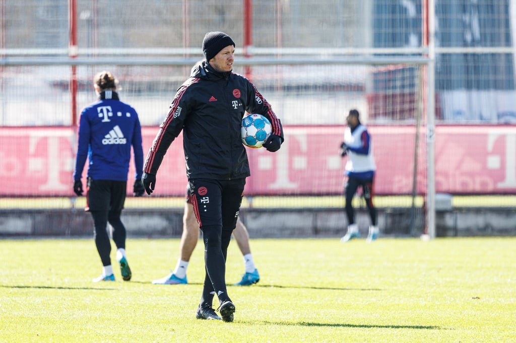 Bayern-Trainer Julian Nagelsmann geht mit einem Ball unter dem Arm über den Trainingsplatz an der Säbener Straße.