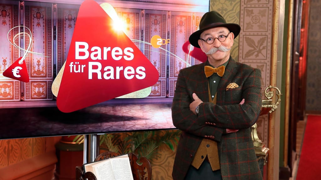 Moderator Horst Lichter steht neben dem Logo der Sendung „Bares für Rares“.