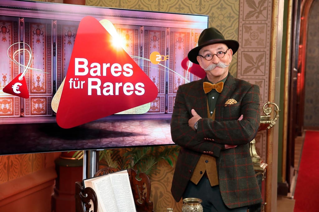 Moderator Horst Lichter steht neben dem Logo der Sendung „Bares für Rares“.