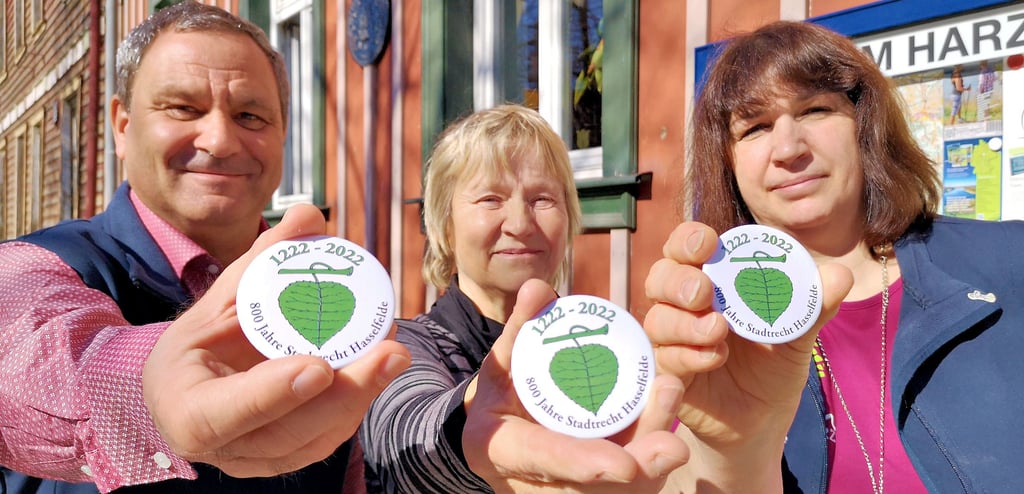 Einen praktischen Nutzen haben diese Buttons, die im Vorfeld des Hasselfelder Ortsjubiläums angefertigt worden: Sie sind magnetisch und dienen auch als Flaschenöffner. Präsentiert werden sie von Thomas Schult, Ilka Kersten und Ines Obermann (von links).
