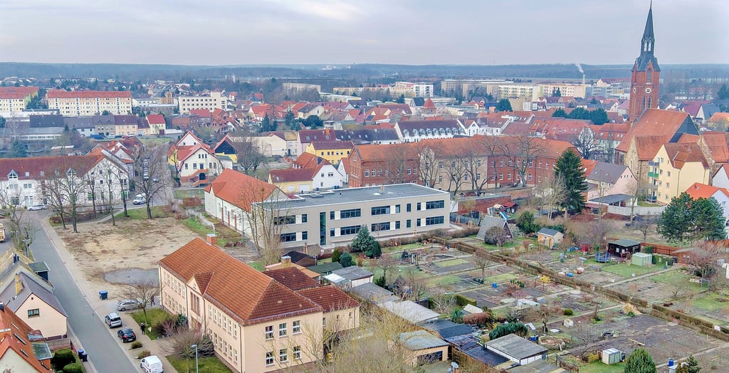 Das neue Schulgebäude des Paul-Gerhardt-Gymnasiums (grau, Bildmitte) grenzt an die Kleingartenkolonie an.