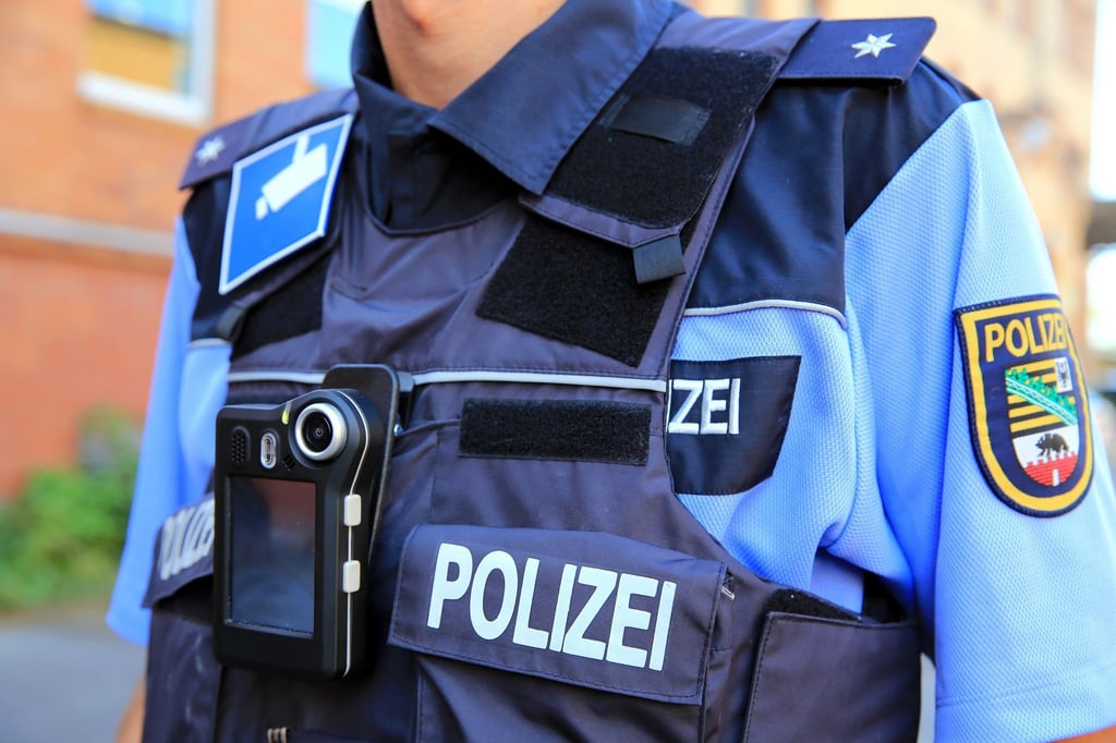 Ein Polizeikommissar trägt eine mobile Miniatur-Videokamera (Bodycam) vor seiner Brust.