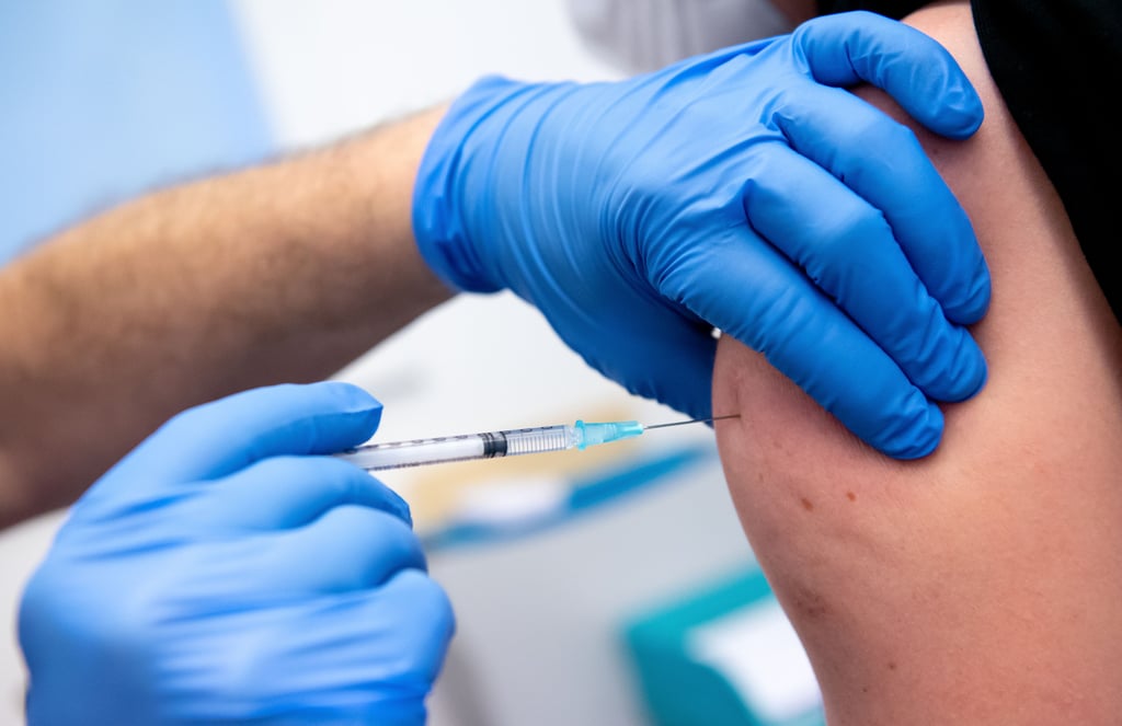 Ein Mitarbeiter einer Klinik wird von einem Kollegen mit dem Corona-Impfstoff von Biontech/Pfizer geimpft.