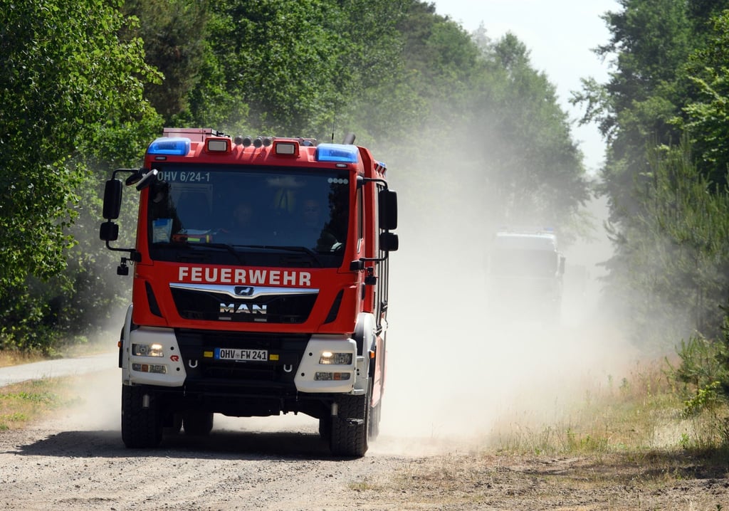 Ein Fahrzeug der Feuerwehr fährt auf dem sandigen Weg durch den Wald.