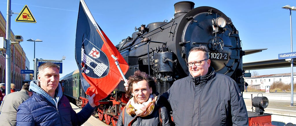 Rübelandbahn-Betriebskoordinator Stephan Nickell, Jeanette Schroeder von der Stadt Halberstadt und Blankenburgs Bürgermeister Heiko Breithaupt (von links) präsentieren nach der Ankunft in der Harz-Kreisstadt die Fahne der Blütenstadt.