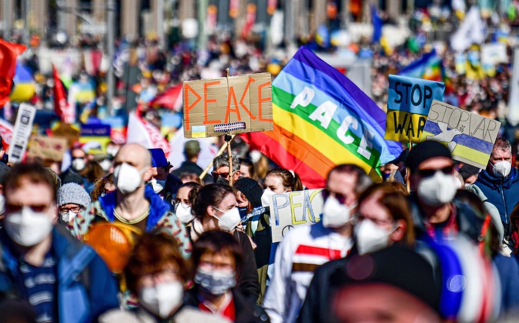 Menschen halten „Peace“-Schilder hoch, während sie an einer Friedensdemonstration gegen den Krieg in der Ukraine protestieren.