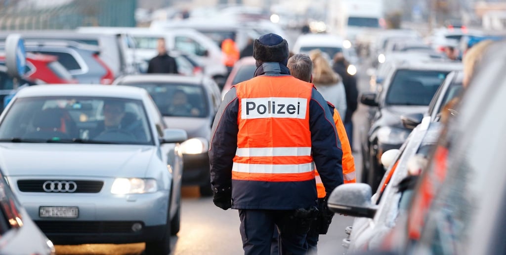 Polizisten laufen während einer Verkehrskontrolle in der schweiz durch Fahrzeugreihen.