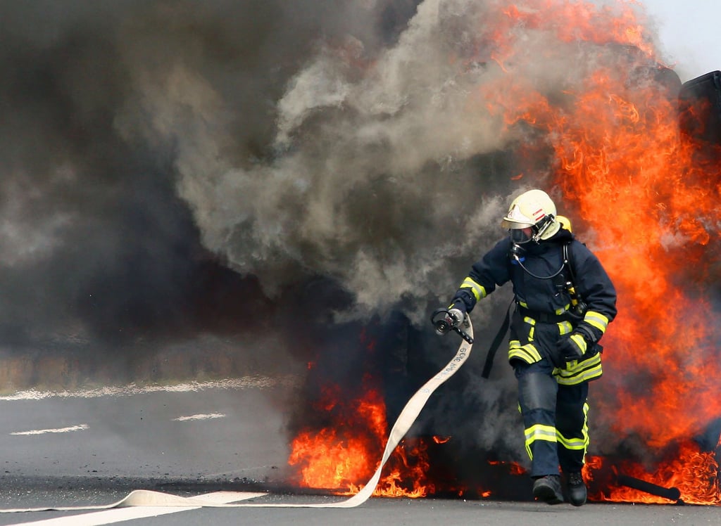 Ein Feuerwehrmann versucht einen brennendes Fahrzeug zu löschen.