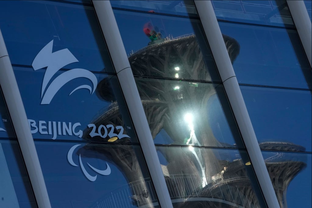 Der Pekinger Olympiaturm spiegelt sich in den Fenstern des Main Media Centers mit dem Logo der Winter-Paralympics 2022.