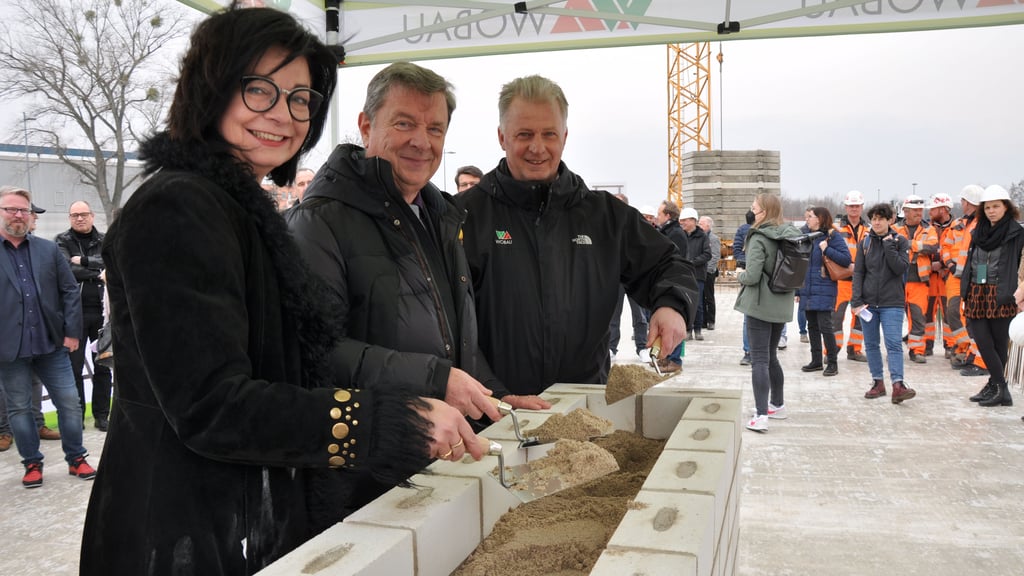 Regina-Dolores Stieler-Hinz (Beigeordnete für Kultur, Schule und Sport), Oberbürgermeister Lutz Trümper und Wobau-Chef Peter Lackner mauern eine Schatulle mit Wobi-Spatz, Volksstimme und Münzgeldsatz in den Grundstein ein.
