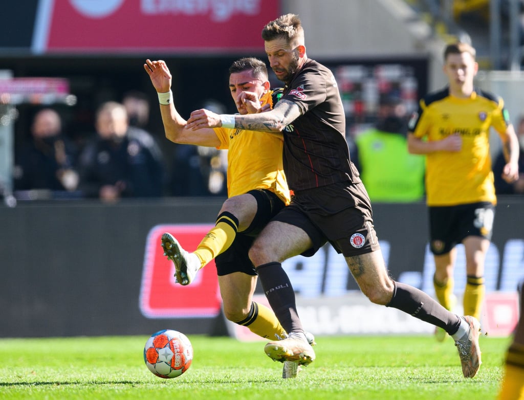 Dynamos Guram Giorbelidze (l) kämpft mit St. Paulis Guido Burgstaller um den Ball.
