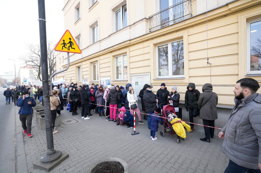 Aus der Ukraine geflüchtete Menschen stehen vor einer Meldestelle Schlange.