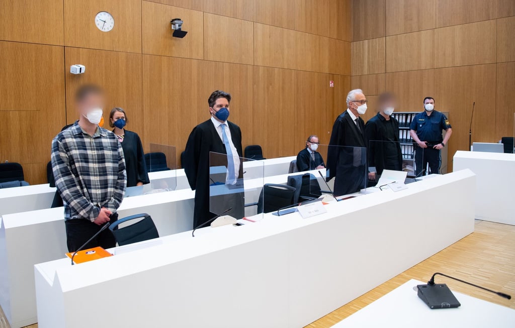Die zwei wegen Mordes angeklagten Männer (l und 2.v.r.) mit ihren Anwälten vor Beginn der Verhandlung im Sitzungssaal.