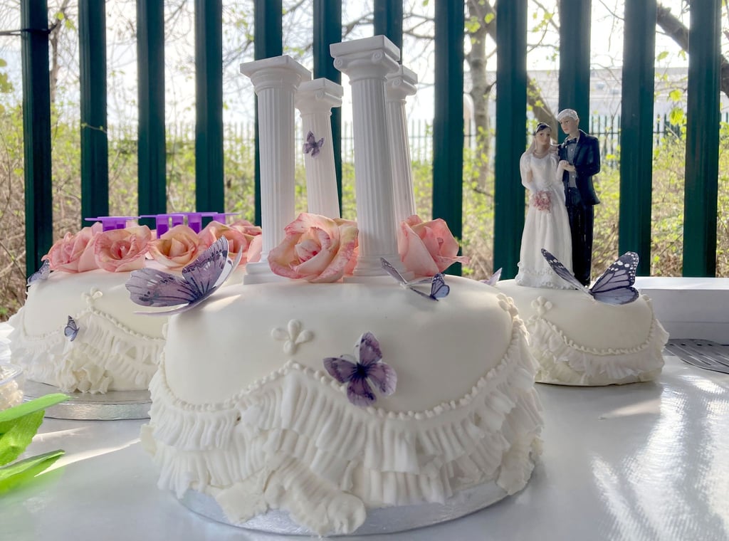 Eine Hochzeitstorte für das Brautpaar steht vor dem Gefängnis auf einem Tisch.