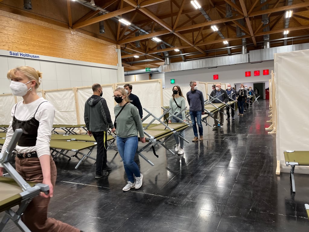 In einem Großeinsatz halfen mehr als 60 Freiwillige beim Aufbau von Feldbetten und Trennwänden in der Messehalle 1, damit hier weitere Ukraine-Flüchtlinge untergebracht werden können.