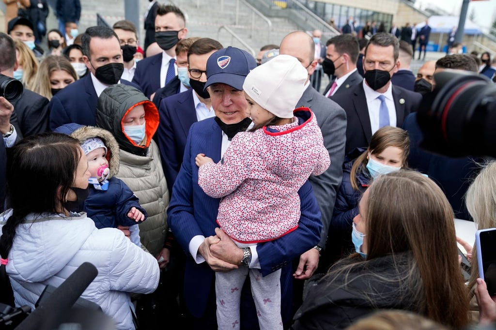 Joe Biden trägt bei seinem Besuch im PGE Narodowy-Stadion, in dem ukrainische Kriegsflüchtlinge untergebracht sind, ein Kind.