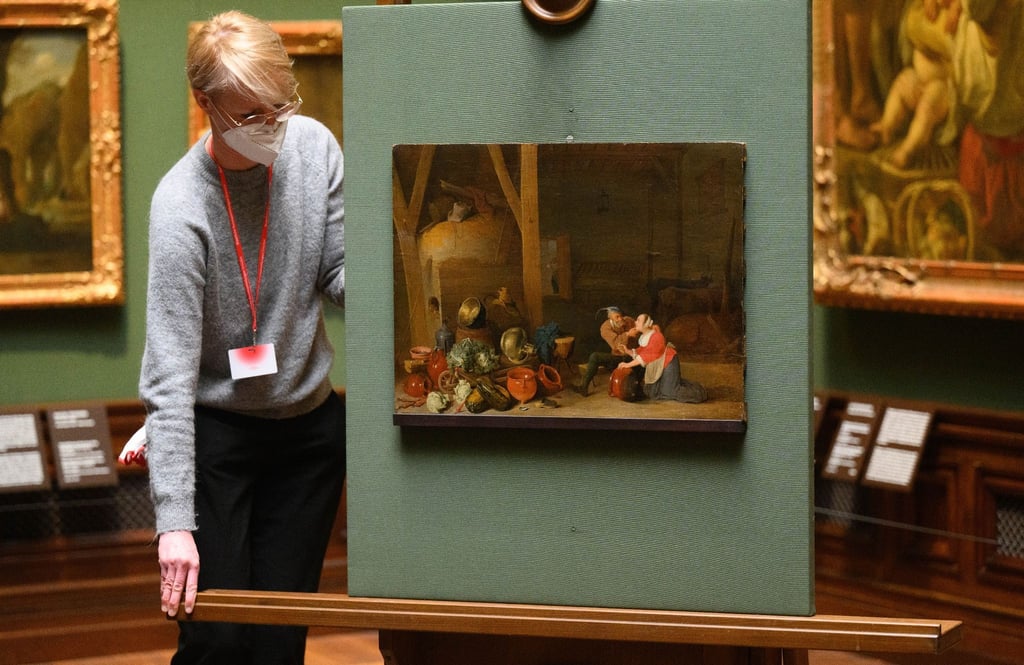 Eine Mitarbeiterin der Staatlichen Kunstsammlungen schiebt das Gemälde mit dem Titel „Ein Alter umarmt die Magd im Stall“ des Malers David Teniers des Jüngeren (1610–1690) in der Gemäldegalerie Alte Meister an seine Position.