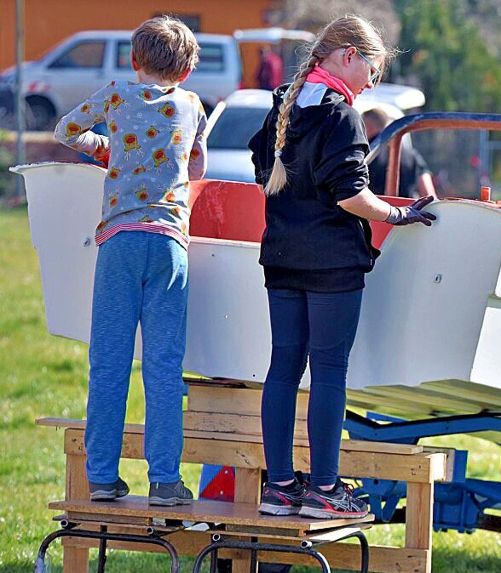 Annabell und Nick schleifen die alte Farbe vom Motorboot der Trainer ab.