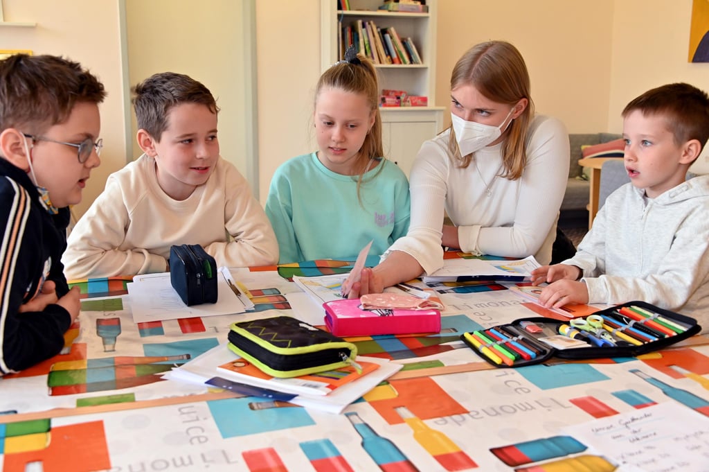 Ivan, Mykyta, Sonja und Hlib (von links) gehen seit kurzem in die Evangelische Grundschule in Magdeburg. Geborgen fühlen sie sich hier. Mit Lehramtsstudentin Anna Fiedler lernen sie jeden Morgen Deutsch, bevor sie in die Klassen mit ihren deutschen Mitschülern gehen.Foto: Uli Lücke