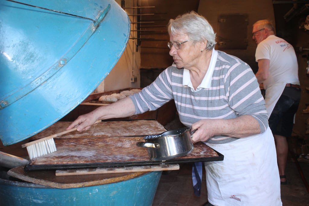 Überwiegend für den Eigenbedarf des Darlingeröder Backteams werden nach den Broten einige Bleche Zuckerkuchen abgebacken. Christine Stier überstreicht die frisch aus dem Ofen genommenen Bleche mit Sahne.