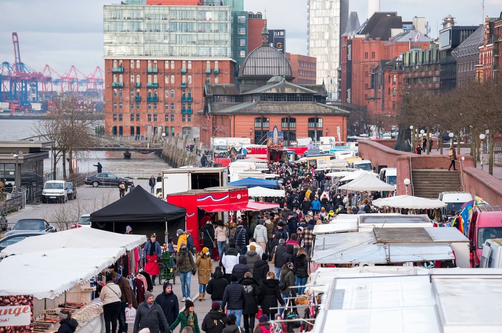 Besucher gehen am Morgen über den Hamburger Fischmarkt an der Elbe. er ist am Sonntag wieder in vollem Umfang gestartet.