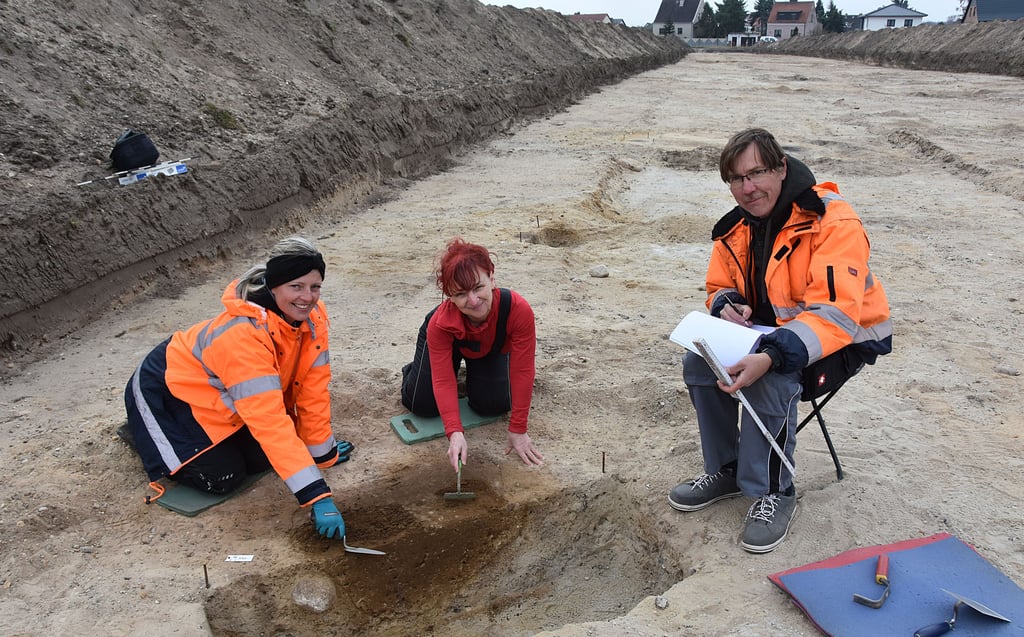 Grabungshelferin Claudia Bodenstedt (l.) und Anett Roisch, Praktikantin für einige Stunden, legen einen Befund frei. Archäologe Marcel Röder dokumentiert die Arbeit auf dem Gelände der Ausgrabungen an der Bülstringer Straße.