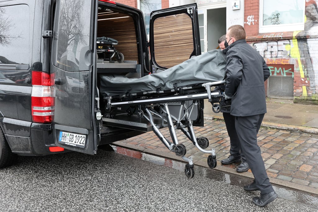 Bestatter bringen eine von zwei Leichen aus einem Mehrfamilienhaus in einen Transporter. In einem Haus nahe dem Bahnhof Hamburg-Altona sind am Dienstag Schüsse gefallen. Die Polizei geht von einem erweiterten Suizid aus.