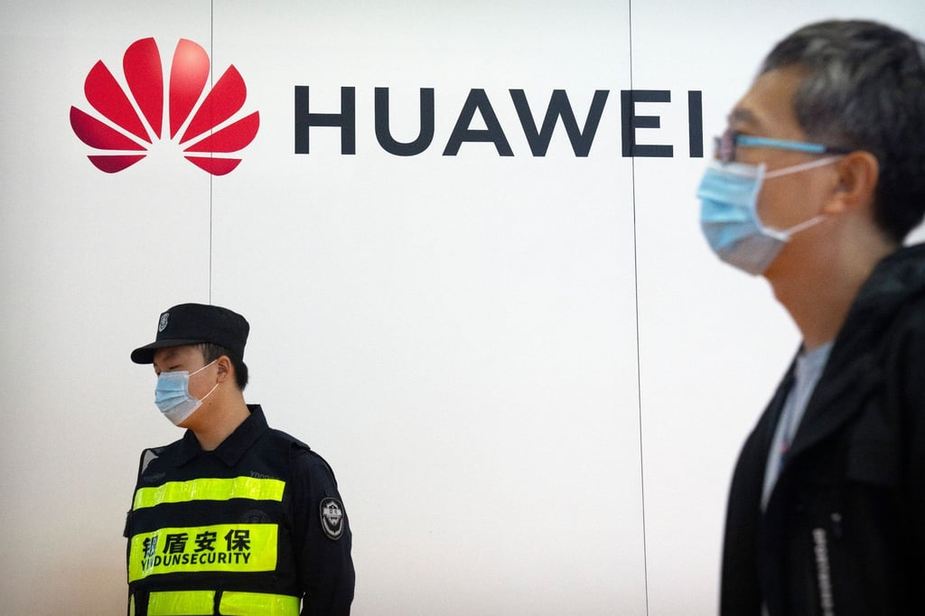Ein Wachmann steht auf der PT Expo in Peking an einem Stand des chinesischen Technologieunternehmens Huawei.