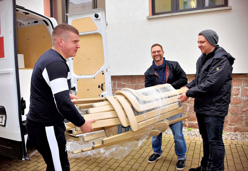 Der Integrationskoordinator der Hochschule Anhalt, Tristan Dornberger (Mitte), und die Studenden Maksim Iushchenko (rechts) und Bohdan Zadoienko laden Möbelspenden für ukrainische Flüchtlinge in der Sporthalle der Hochschule ab.