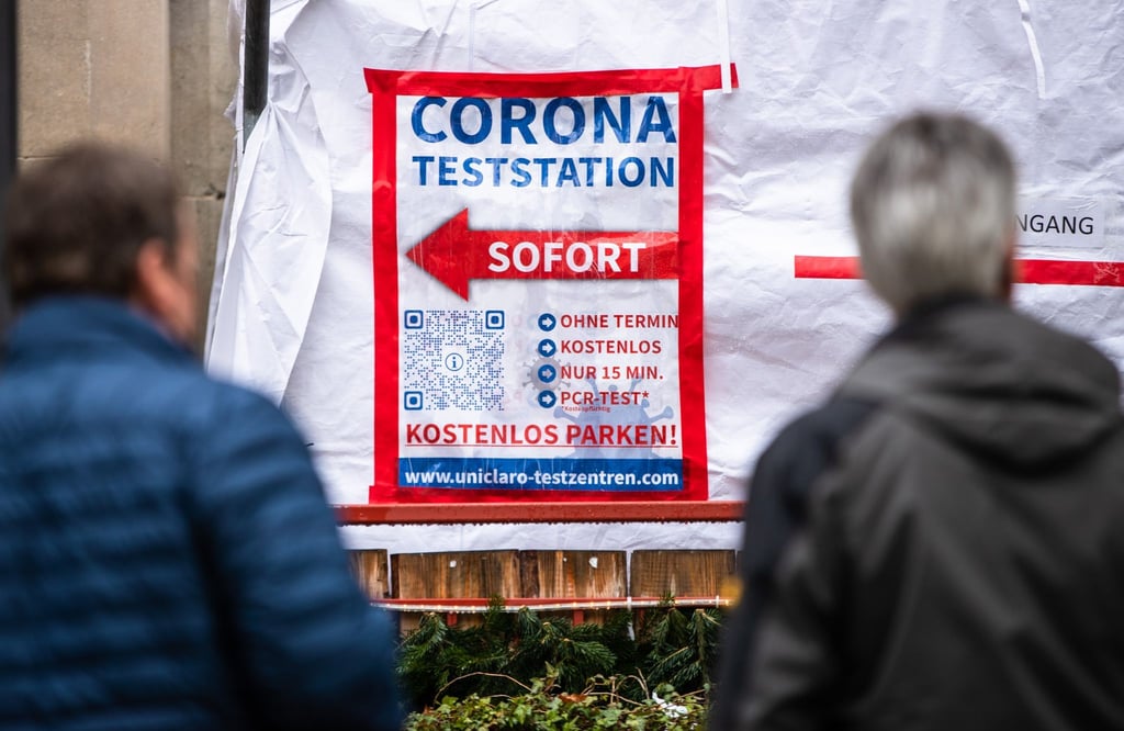 Menschen warten in der Stuttgarter Innenstadt vor einem Corona-Testzentrum auf ihren Abstrich.