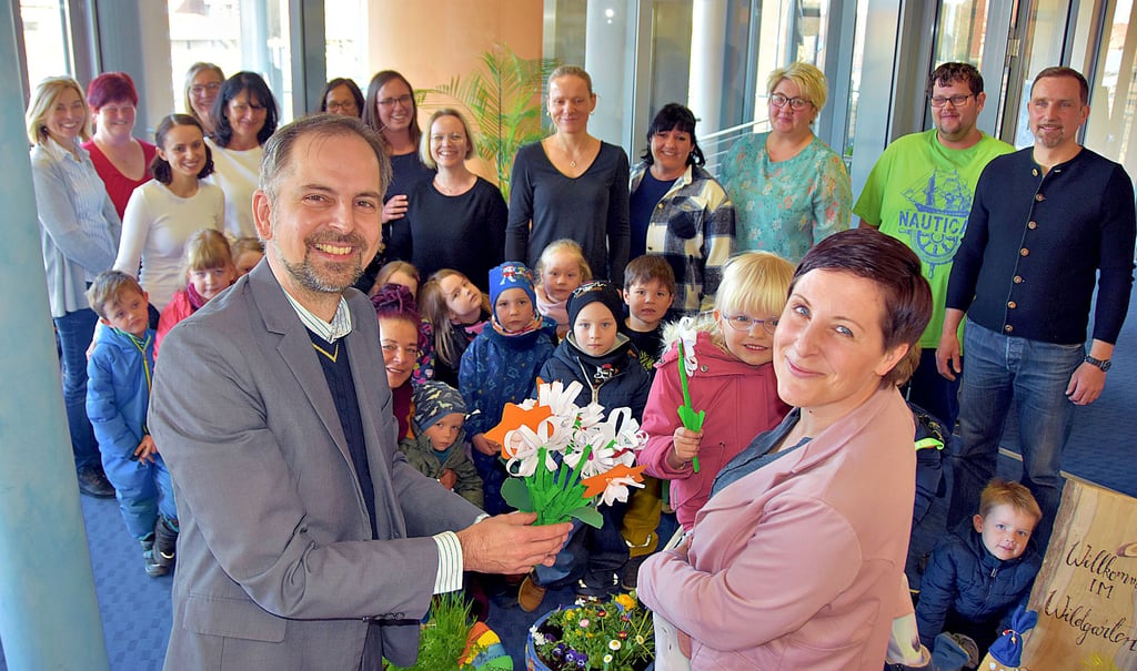 Zum Abschied überreicht Stefanie Heidemann-Müller gemeinsam mit der kleinen Lina eine von vielen gebastelten Blumen an Flechtingens Verbandsgemeinde-Bürgermeister Mathias Weiß. Geschenke gibt es auch von den Kita-Leiterinnen und Erziehern.