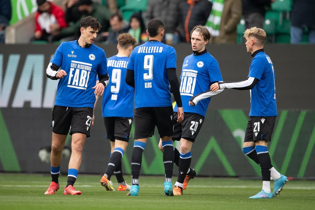 Spieler von Bielefeld tragen beim Aufwärmen ein Trikot mit der Rückennummer 9 und der Aufschrift „Gute Besserung Fabi“.