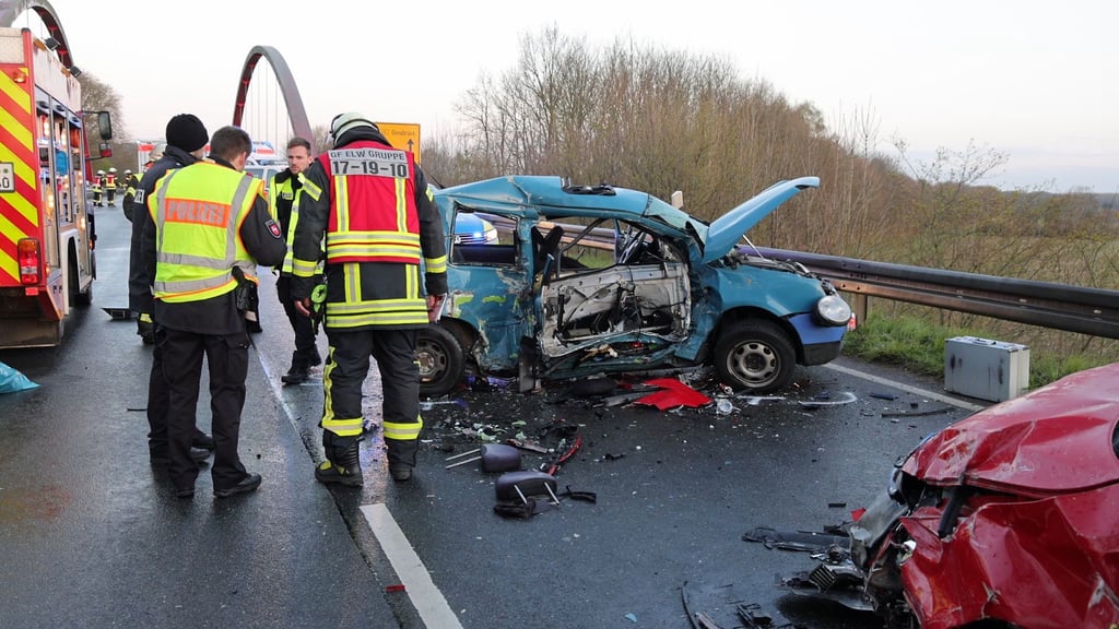 Rettungskräfte von Polizei und Feuerwehr stehen neben den Trümmern von zwei Fahrzeugen nach einem tödlichen Unfall.