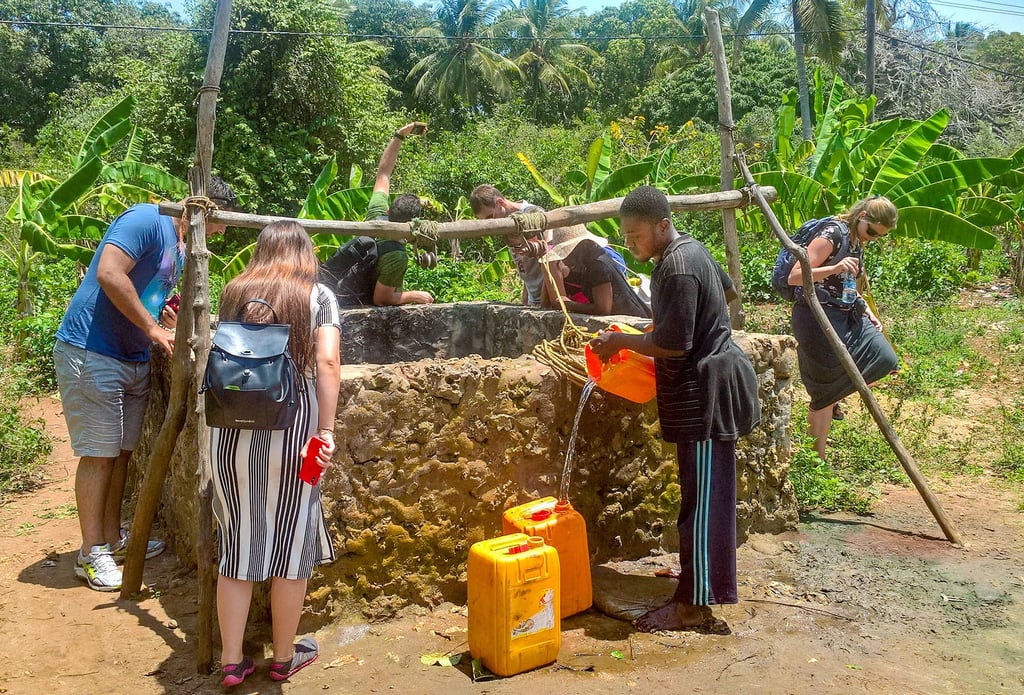 Freiwillige Helfer und Einheimische schöpfen aus einem Brunnen in Uzi Island Trinkwasser.