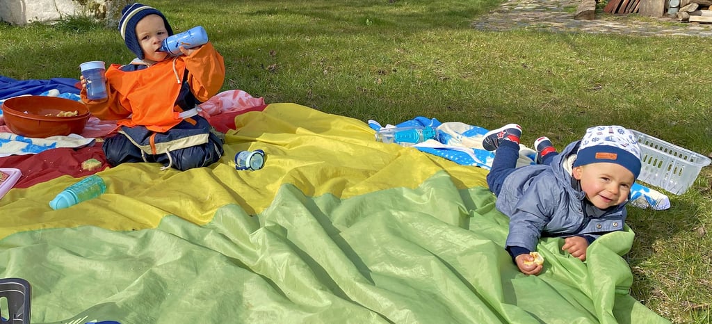 Der einjährige Emil (rechts), Jüngster der „Mühlenspatzen“, und der zweijährige Thies genießen das Picknick im Freien. Bei schönstem Frühlingswetter mit viel Sonne schmeckt der Kuchen gleich doppelt so gut. Der Ausflug ist Teil der Spezial-Woche in der Kita, die anlässlich des anstehenden Osterfestes veranstaltet wurde.