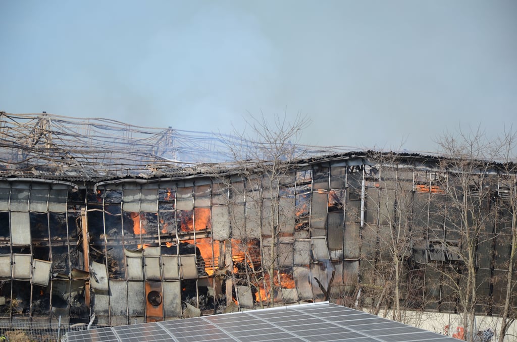 Die Lagerhalle an der Straße brennt immer noch.