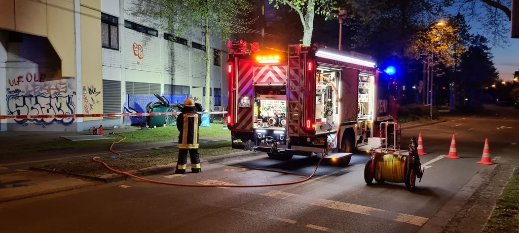 Ein Feuerwehrmann steht neben dem Wrack eines Autos, in dem zwei junge Männer aus der obersten Etage eines Parkhauses gestürzt und ums Leben gekommen sind.
