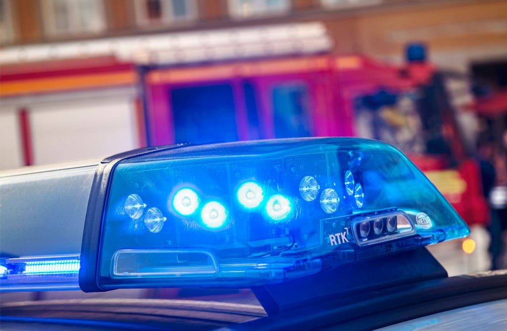 Blaulicht leuchtet vor Fahrzeugen von Polizei und Feuerwehr.