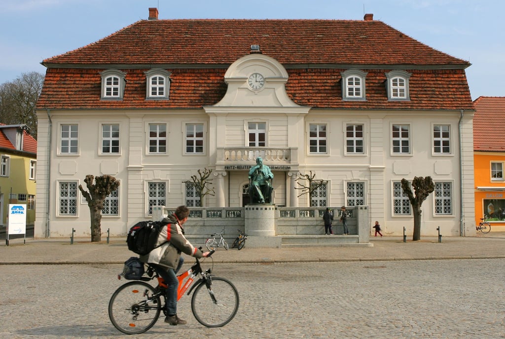Das Fritz-Reuter-Literaturmuseum mit dem Denkmal in doppelter Lebensgröße davor in Stavenhagen.