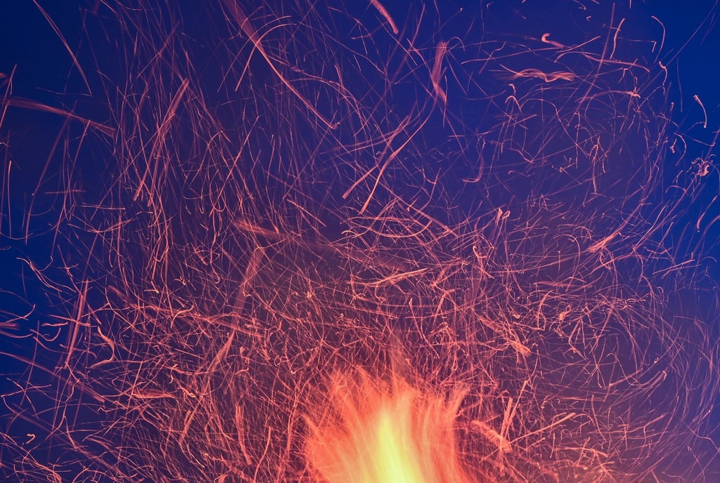 Funken eines Osterfeuers vor dem blauen Abendhimmel. In Hessen ist beim Aufbau eines Osterfeuers ein Mann ums Leben gekommen.