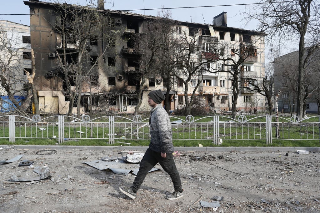 Ein Mann geht in der Nähe eines durch Beschuss zerstörten Wohnhauses in Mariupol.