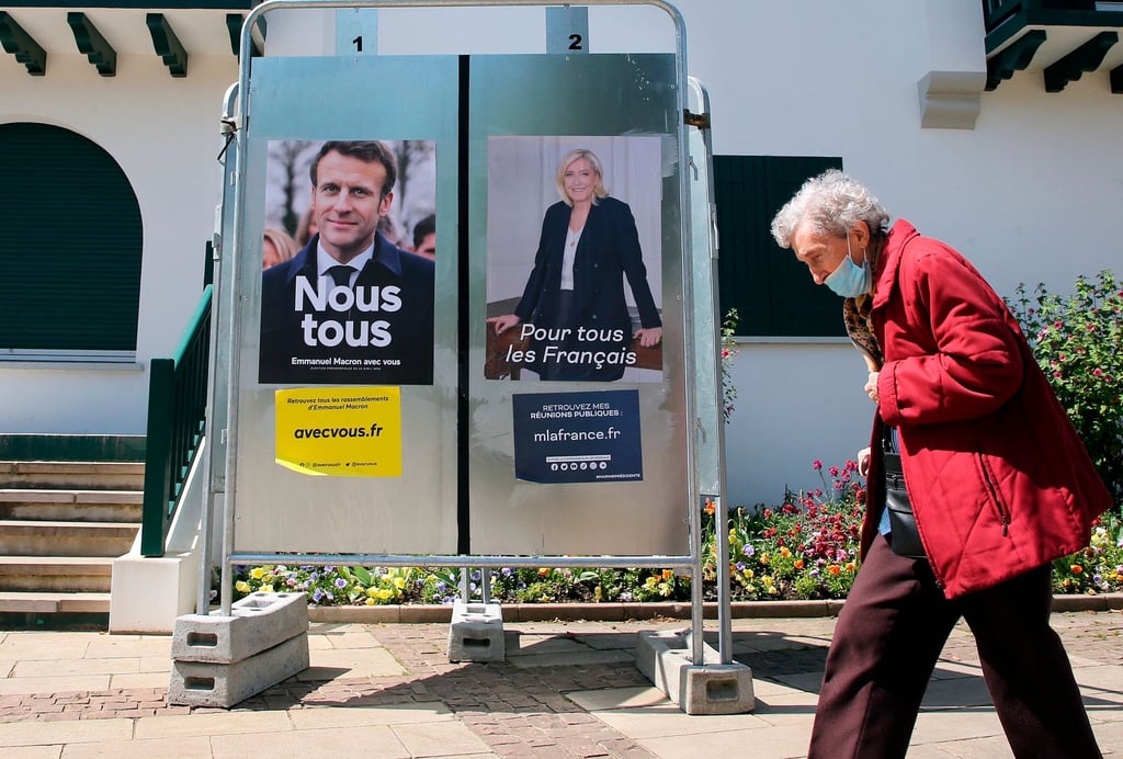 Eine Frau geht im Südwesten Frankreichs an Wahlkampfplakaten der französischen Präsidentschaftskandidaten Macron und Le Pen vorbei.